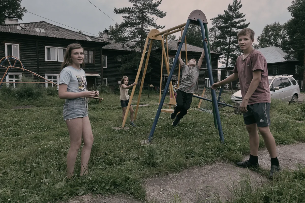 Chegdomyn, Russia. 2019. Children among old residential wooden barracks.
