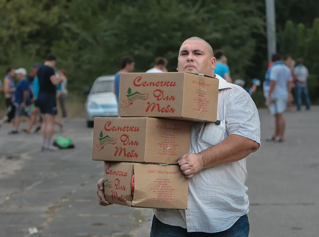 A man carries boxes of sunflower seeds to the stadium before the match.